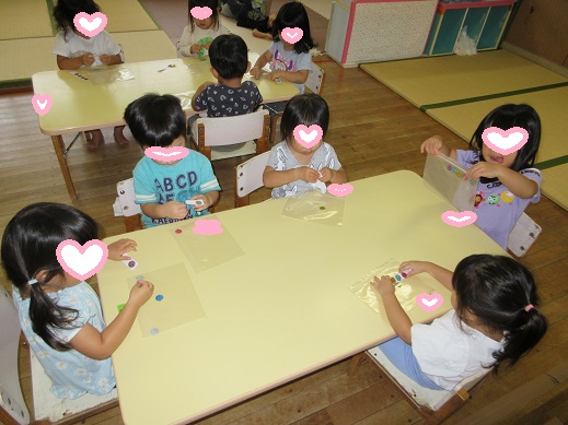 袋に大小さまざまの大きさのシールを貼る2歳児