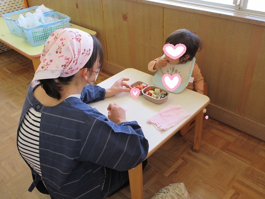 お弁当に手を伸ばし自分で食べる1歳児