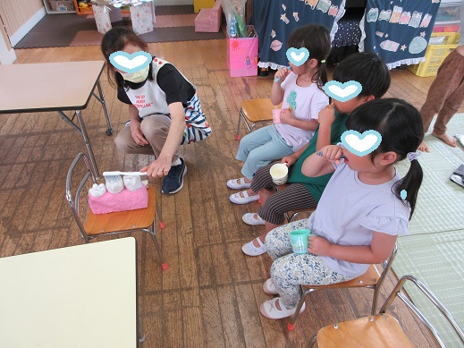 6歳臼歯の模型を使いながら、看護師が子どもたちに歯磨き指導をしているところ