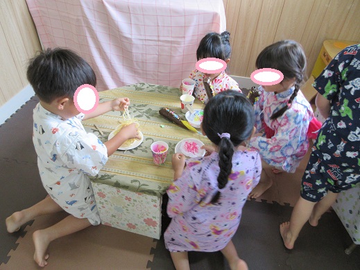 縁日ごっこで買った焼きそばやかき氷を食べる真似をする様子