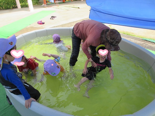 先生に水面で揺らしてもらい、水の感触を楽しむ4歳児