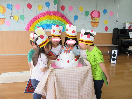 大きな誕生日ケーキのロウソクを吹き消す真似をする様子