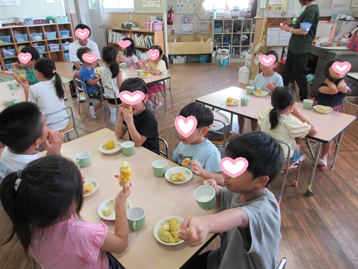 収穫したとうもろこしを食べて喜ぶ子どもたち