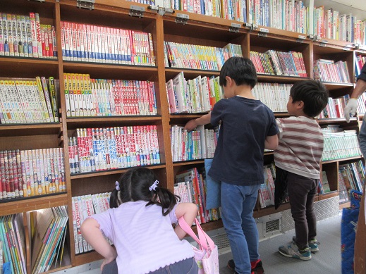 本棚に並ぶたくさんの本を見て心弾ませる5歳児