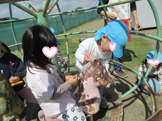 固定遊具の馬に草を採ってきて食べさせてあげる2歳児