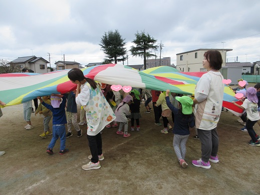 パラバルーンの中に入れてもらう3・4歳児