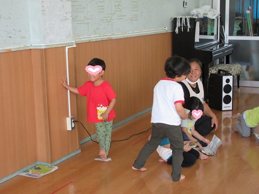 小さくなった新聞紙の上で落ちないように、壁に手を付き反則する子
