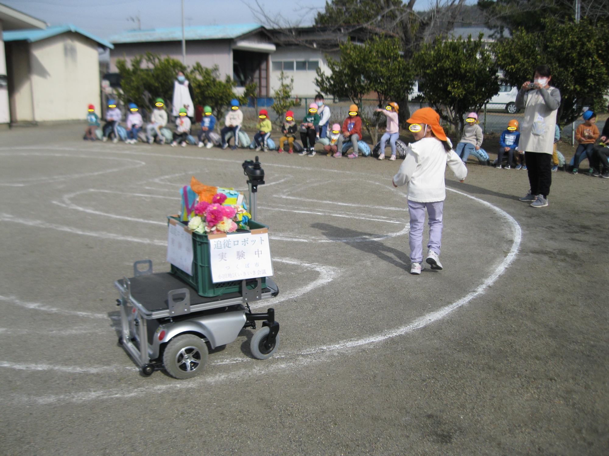 ロボットが子どもの後について動いています。
