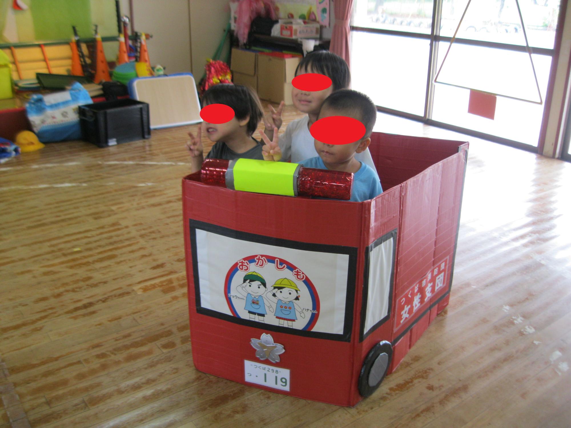 子どもたちが手作りの消防車に乗せてもらっています。