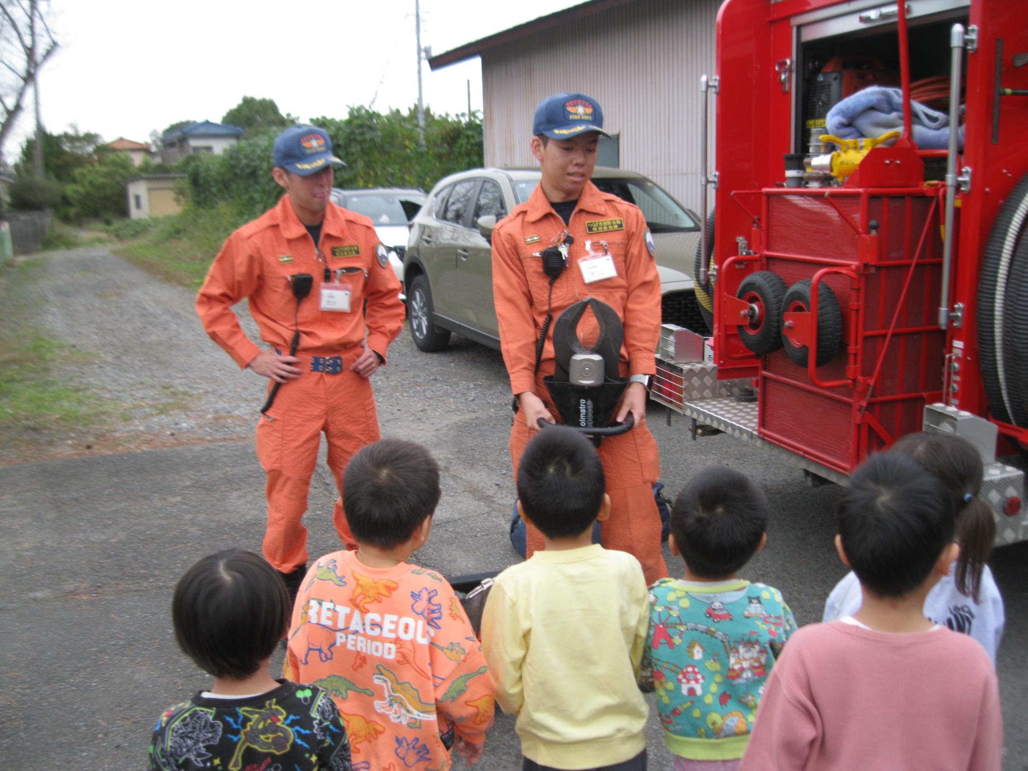 消防車の中の道具を見せてもらい、使い方をおしえてもらっているところです。