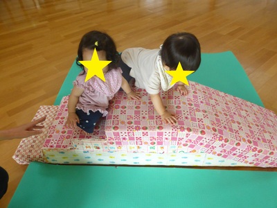 屋内に設置された小さなすべり台を2名の子どもが登って遊んでいる写真