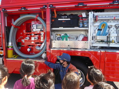 消防車についている様々な装備品の説明をする消防署員の写真
