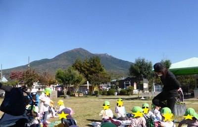 青空の下みんなでお弁当を食べる子どもたちの写真