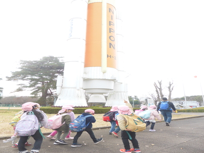 エキスポセンターのロケットの前を歩く子どもたちの写真