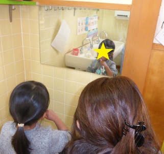 鏡を見ながら説明されたはみがきを実践する子どもたちの写真