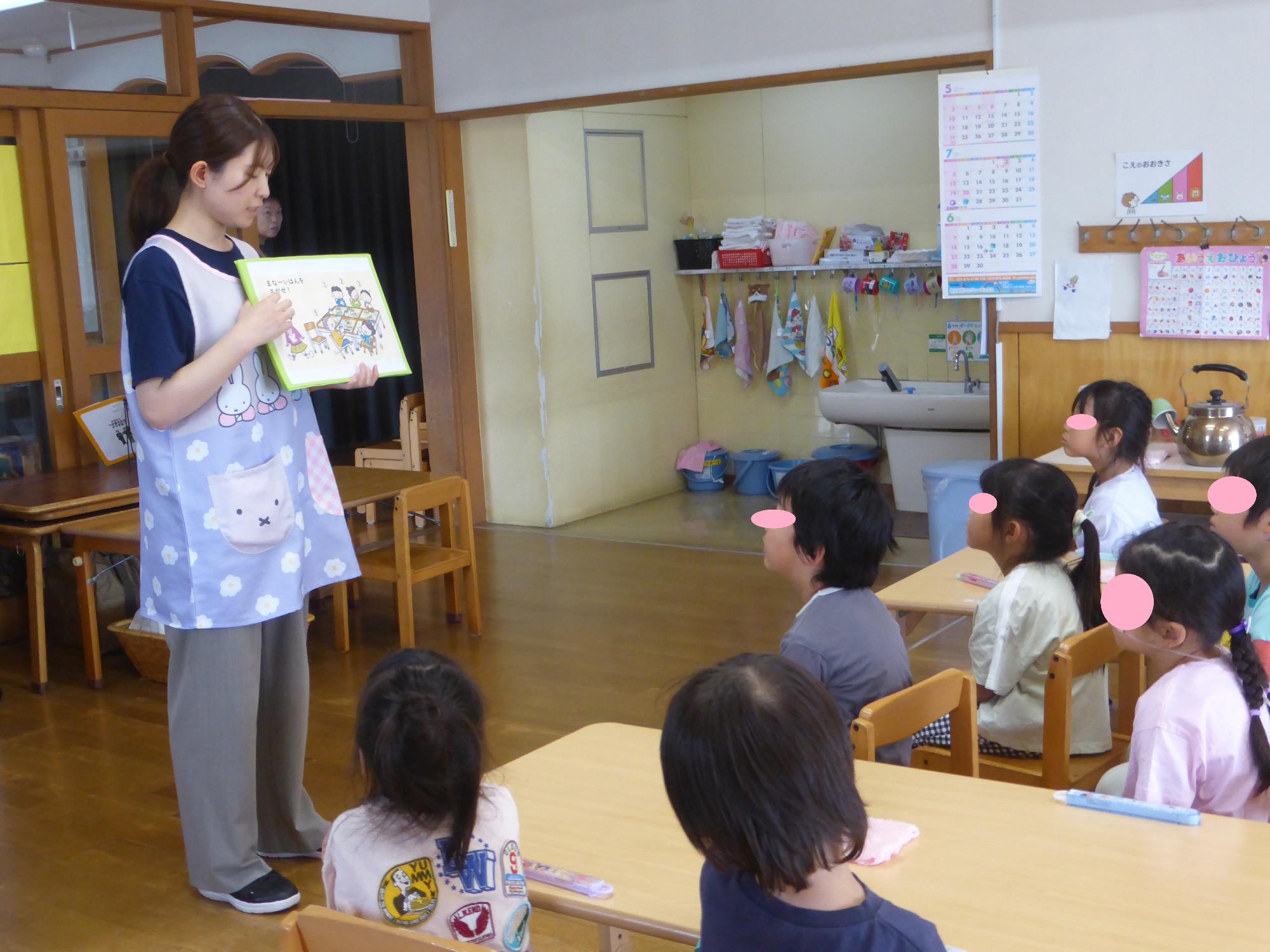 栄養士が子どもたちに、食事のまなーを絵本を読んで知らせています。
