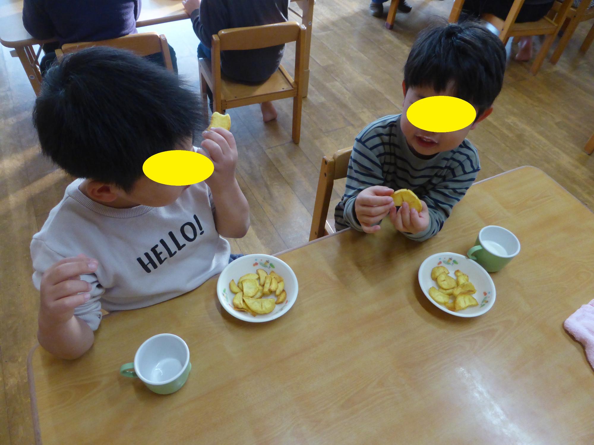 年長児がおいしそうにいもけんぴを食べています。