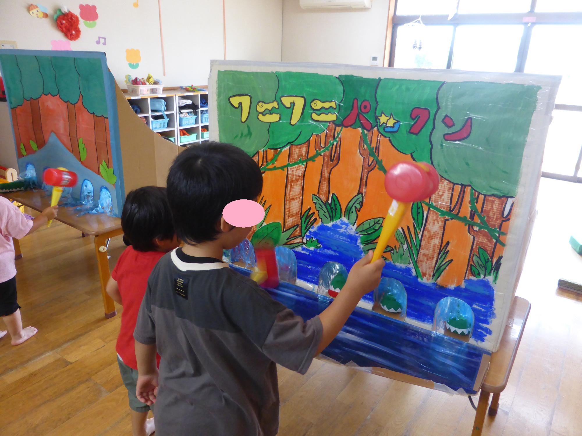ワニワニパックンのゲームで、子どもたちが、ハンマーで出てくるワニをたたいています。
