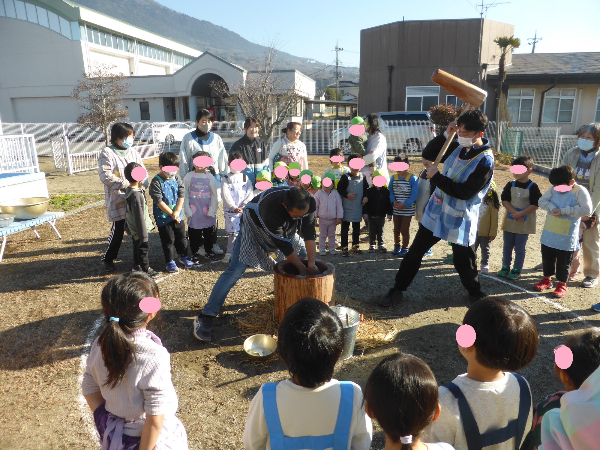 杵と臼を使って、餅つきをしています。子どもたちも「よいしょ！」と掛け声をかけています。