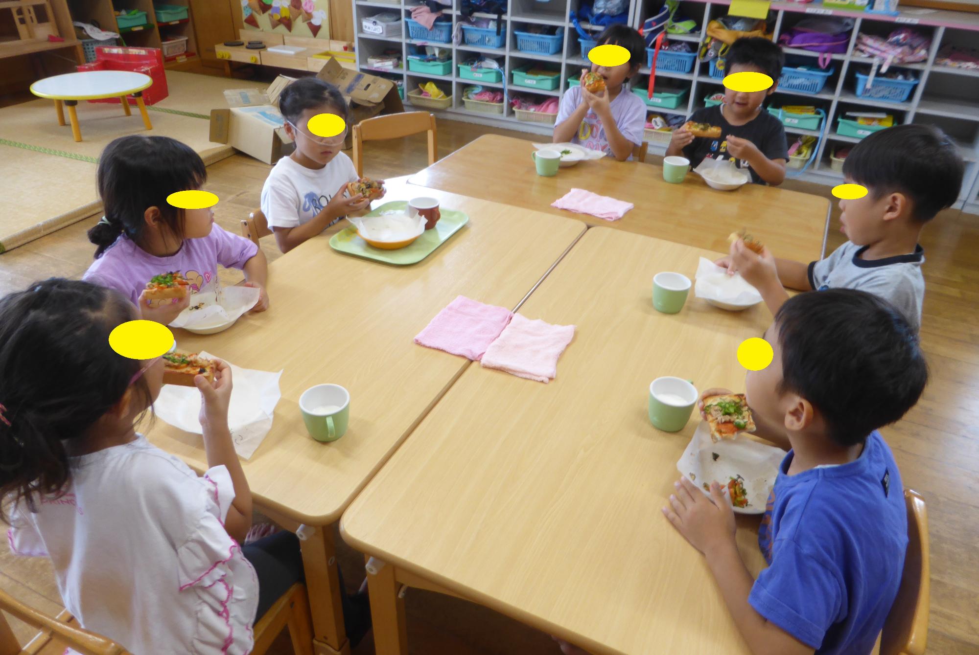 みんなで出来上がったピザを食べています。