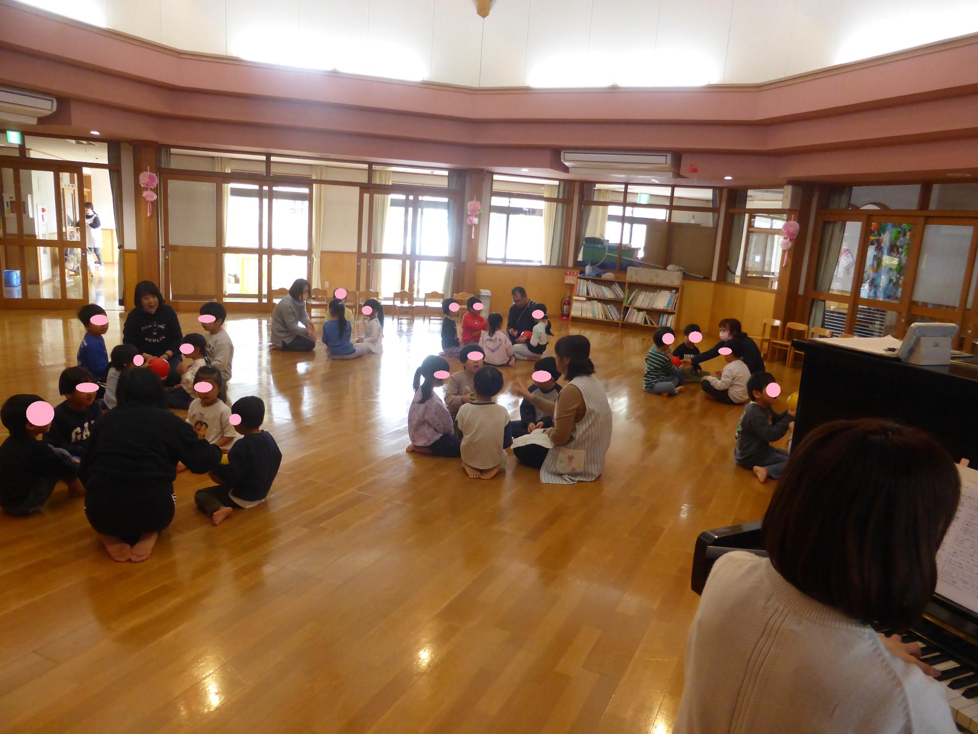 5人組で丸くなってすわり、ボールを順番に回しています。