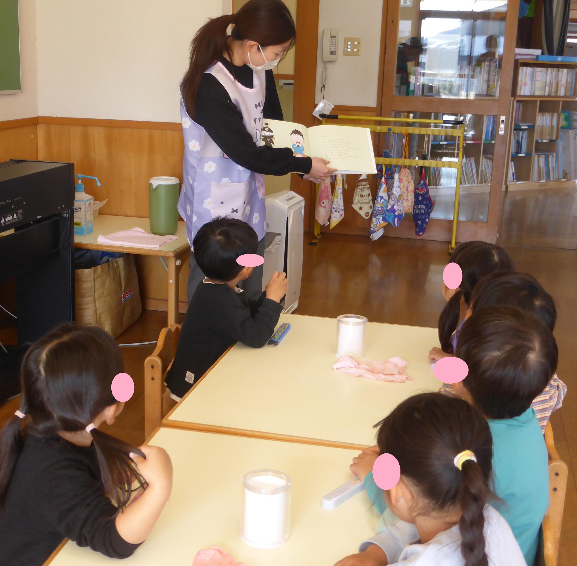 栄養士が子どもたちに絵本を読み聞かせしています。