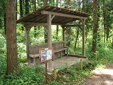 木々に囲まれた中央に屋根付きのベンチが設置されている写真