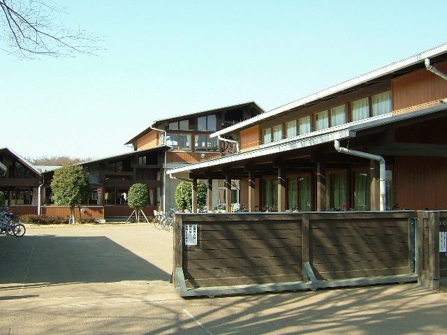スライド式の門の先に木造の小学校の校舎が連なって建っている外観写真
