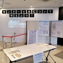 壁に「センタービルについて考えよう！」の文字と、パネルに展示等の資料が貼られており、手前のテーブルに資料が置かれたオープンハウスの写真