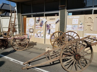 建物のガラス窓に立てかけられた展示物の手前に大八車が展示されている北条市での出展の様子の写真