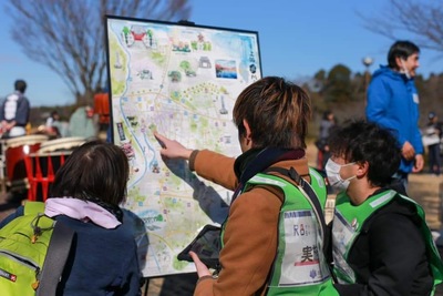 地図ボードを見ながら話をしている3名の後ろ姿の写真