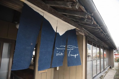 白と紺色であしらわれ「iriai tempo」と書かれたデザインの暖簾がかかっている店舗の入り口の写真