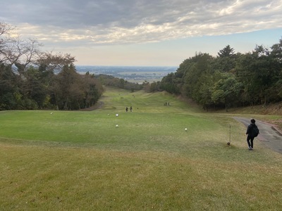 雑木林に囲まれた奥に向かって傾斜になっているゴルフ場に幾つかボールが転がっている写真