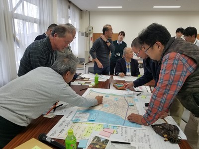 テーブルに置かれた大きい地図を覗き込みながら協議をしている参加者たちの写真