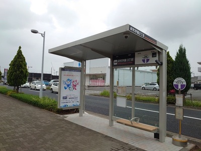ベンチや防犯カメラが設置された広告付きバス停上屋の写真