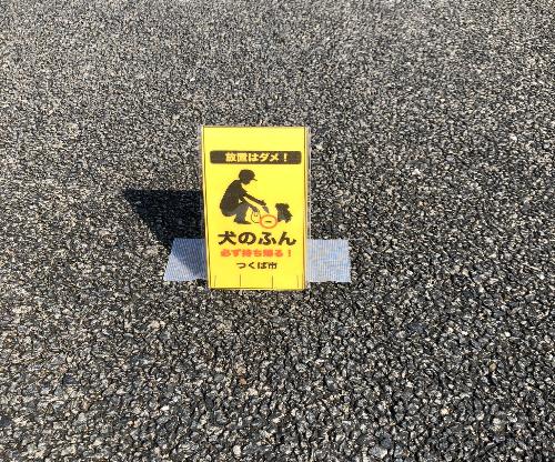 犬のふんの持ち帰りを啓発するイエローカードが地面に貼り付けられている写真