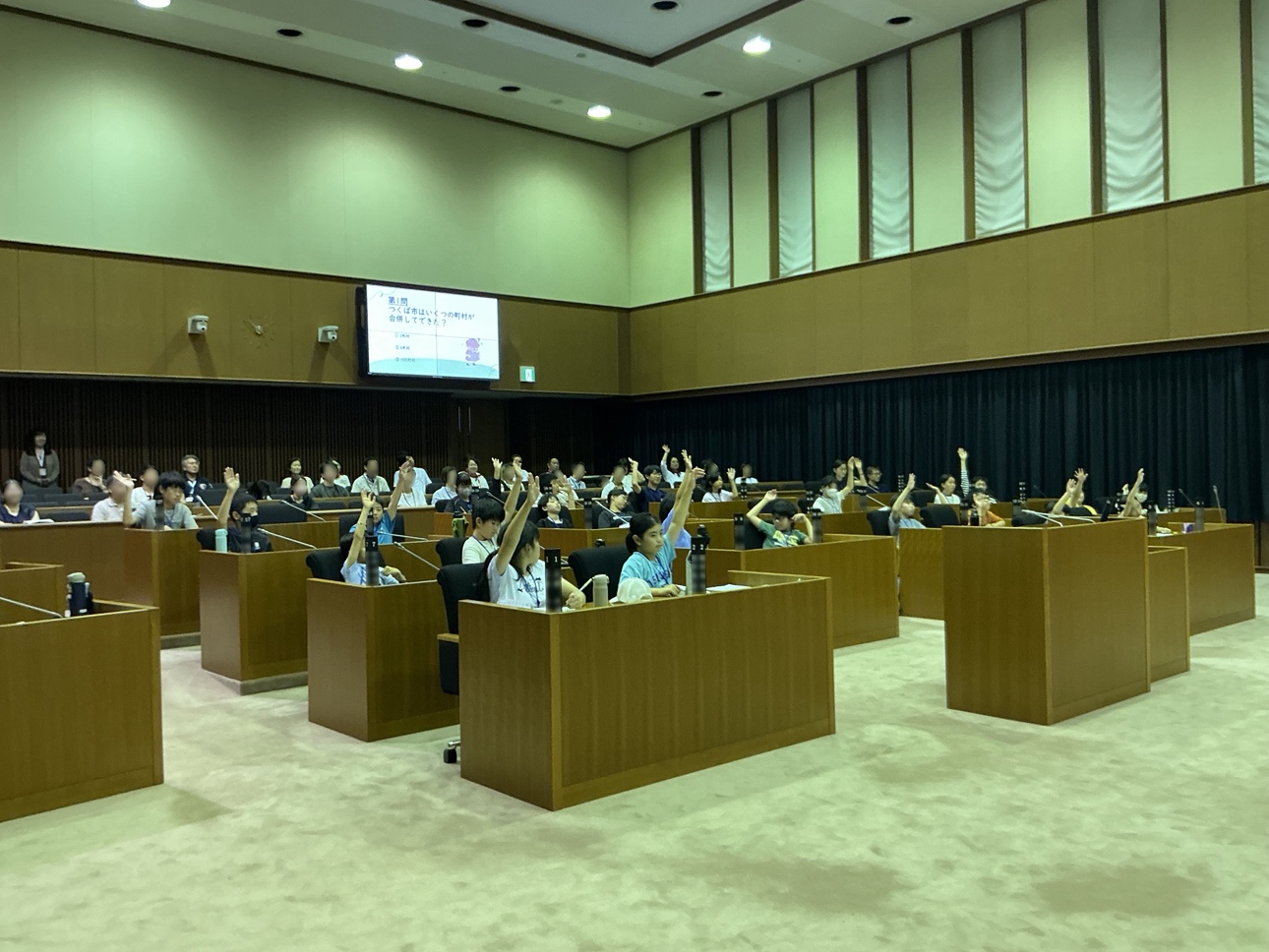 市議会クイズで手をあげる子どもたちの様子