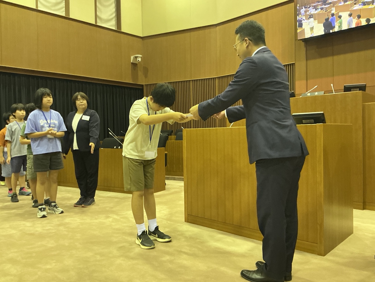 議場で議長から修了証を参加者に進呈する様子