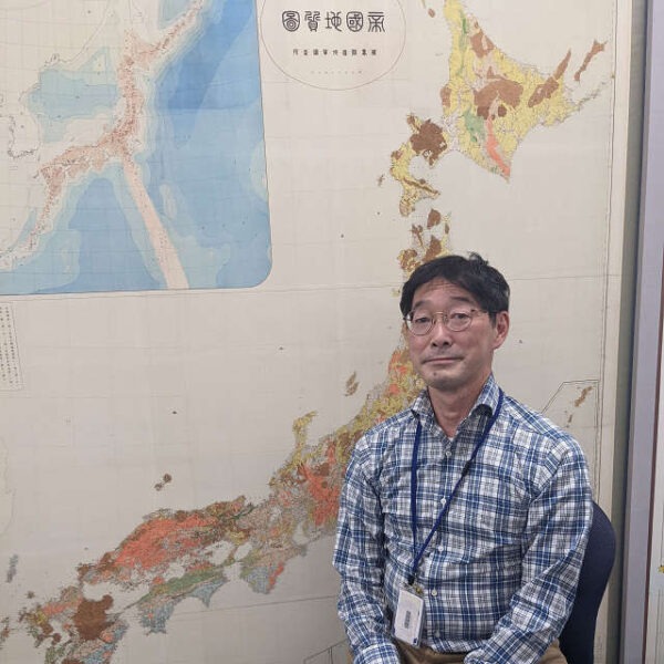 日本地図の前に立つ宮地良典さん