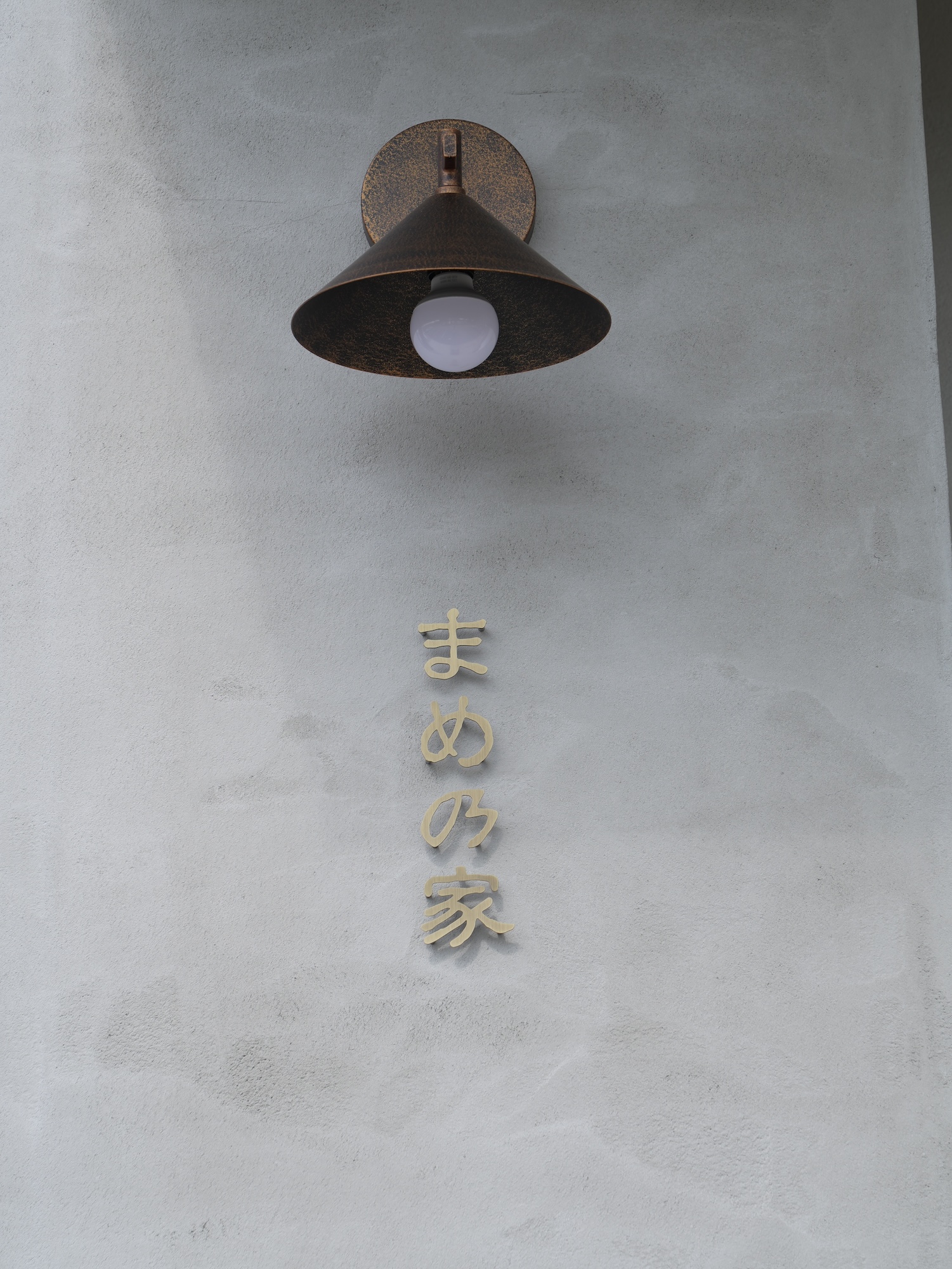 お店の入り口にあるランプと真鍮でつくられた屋号の写真
