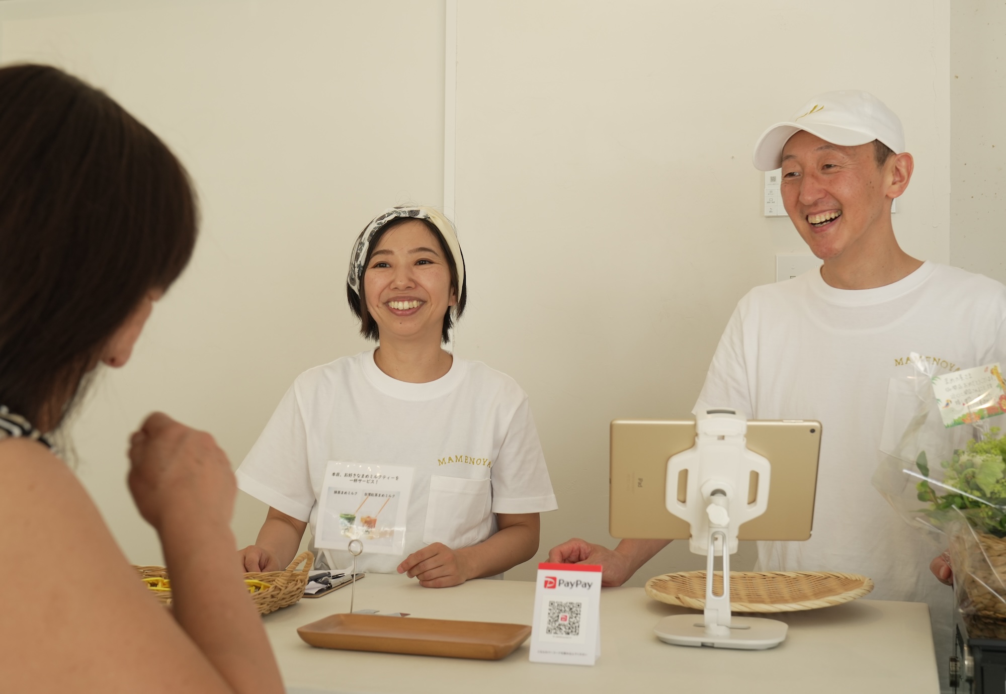 レジカウンターでにこやかに談笑する金原さん夫婦の写真