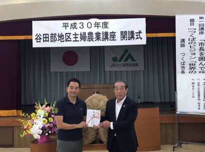 谷田部地区主婦農業講座の開講式で横田組合長から目録の封筒を受け取る五十嵐市長の写真