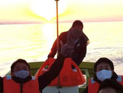 事務局職員と霞ヶ浦の日の出を背景にして撮影した写真