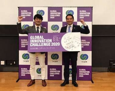 「Global Innovation Challenge2020」と書かれた大きなポスターを2人で一緒にもって記念撮影をする男性の写真。
