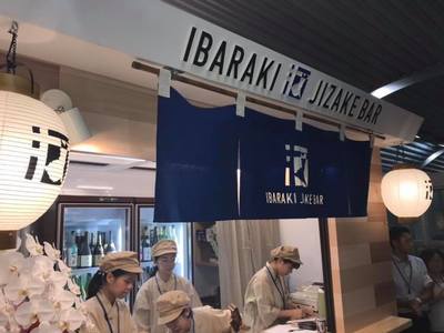 いばらき地酒バーを撮影した写真。「IBARAKI JIZAKEBAR」と書かれたのれんの向こうで働いているスタッフ数名が写っている。