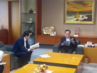 県への要望書提出の写真、資料を読む知事と市長の様子