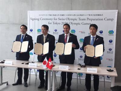 オリンピック締結式で合意書を持って並ぶ、スイス人男性と筑波大学の永田学長と茨城県の大井川知事と五十嵐市長の写真