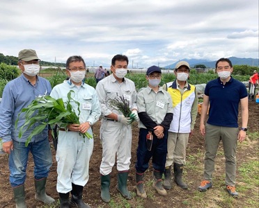 畑の中で野菜を持ち並ぶ男性達と五十嵐市長の写真