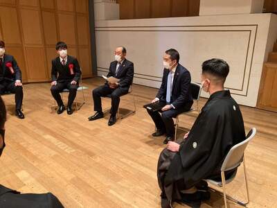 スーツや袴を着た実行委員の方々や市長が輪になって椅子に座り話をしている様子の写真