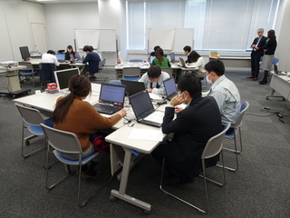 グループに分かれて席につき、ノートパソコンを見ながら話し合いをしている参加者の写真
